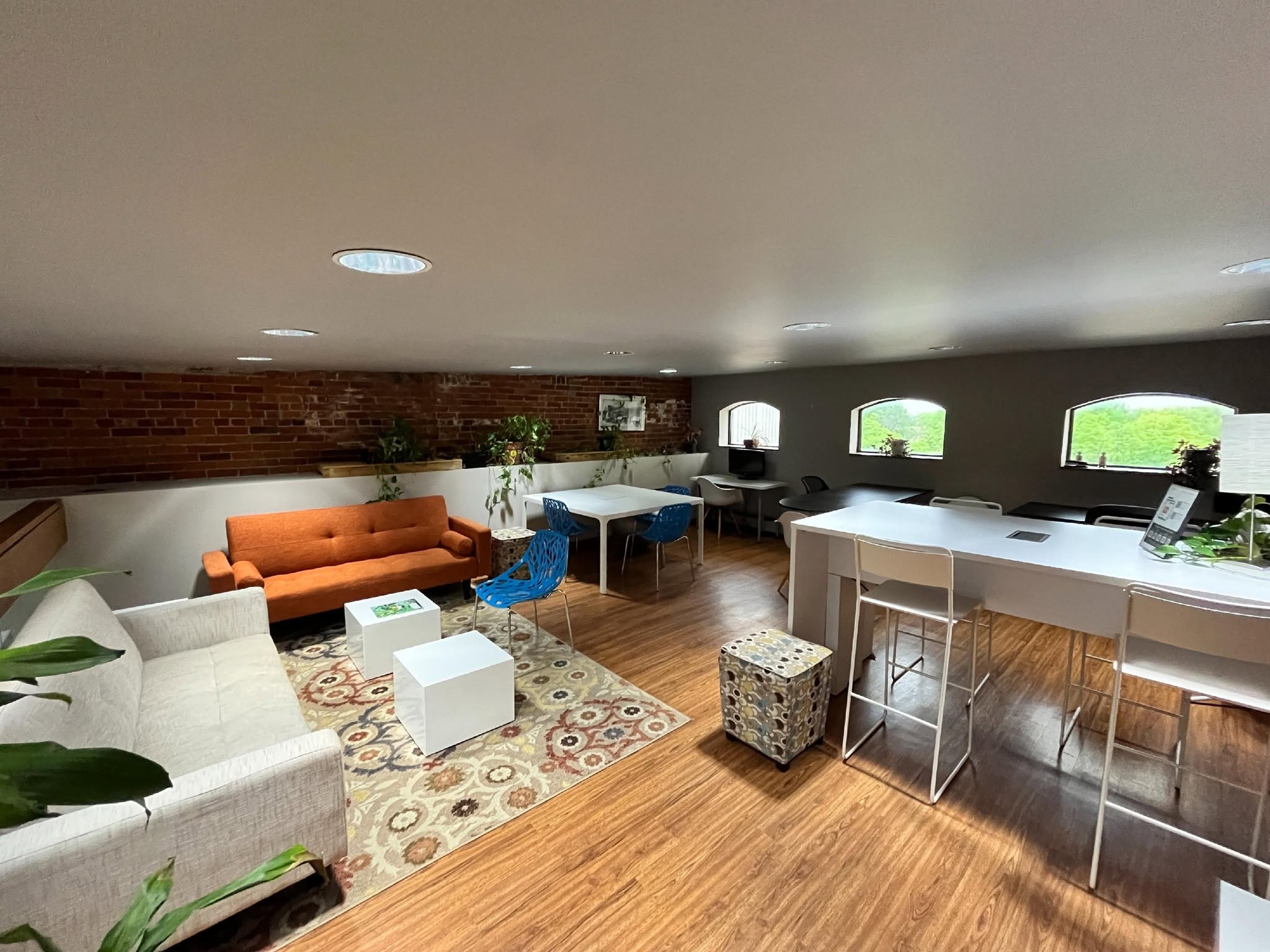 Upper loft workspace with exposed brick, arched windows, and standing desks